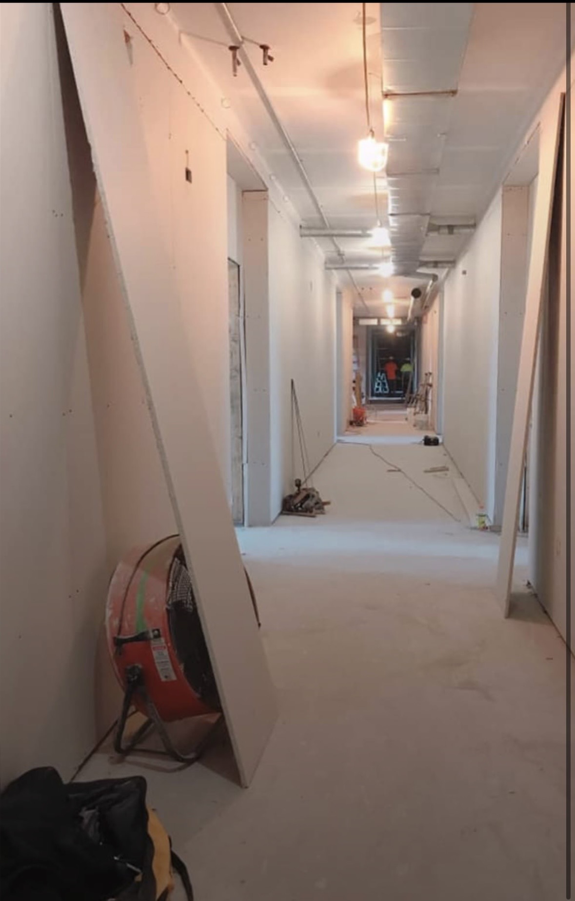 Long hotel-style corridor with finished partition walls and ceiling seams sanded dust-free before paint