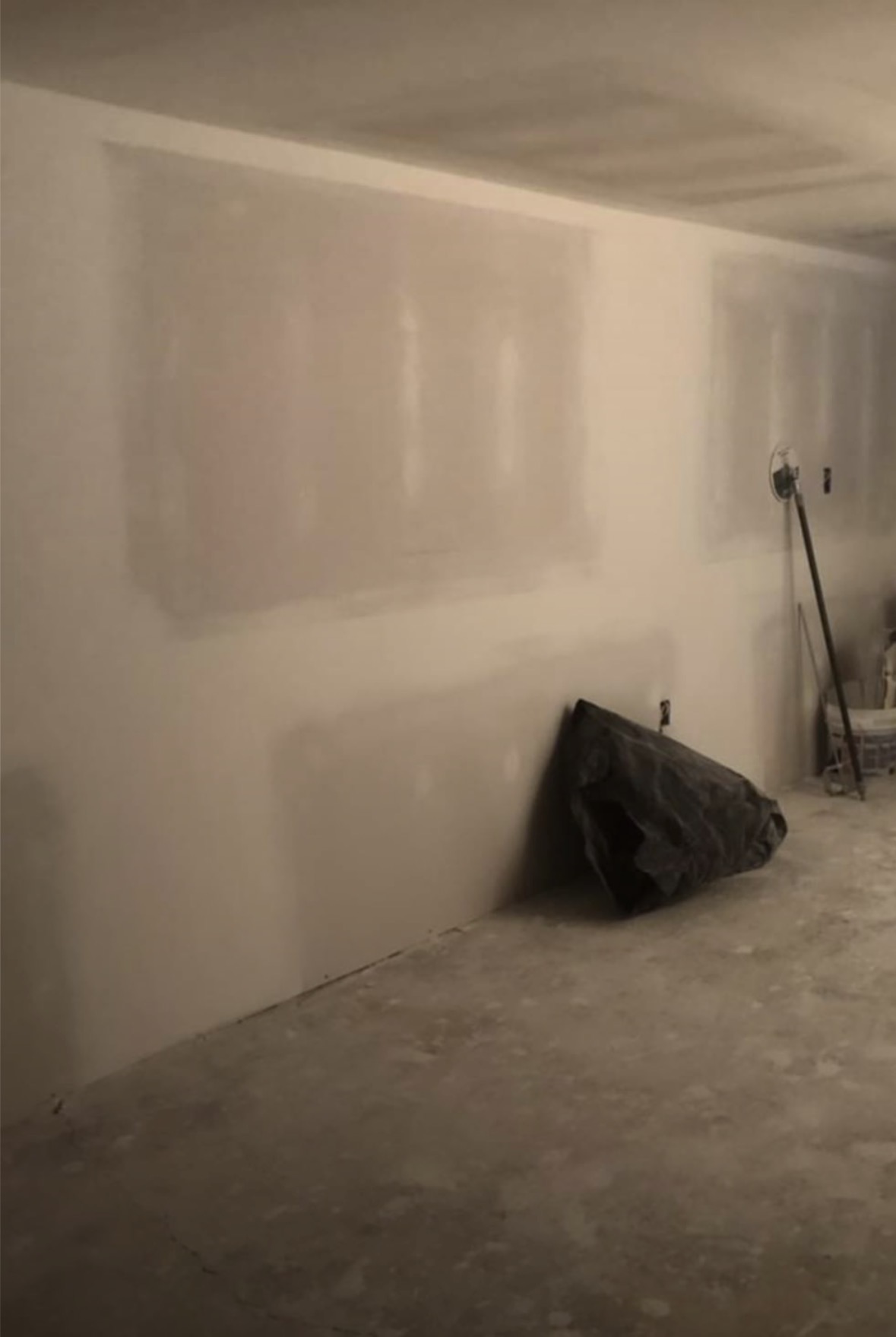 Wide interior wall skim coated and sanded to a seamless finish with no visible joints under raking light