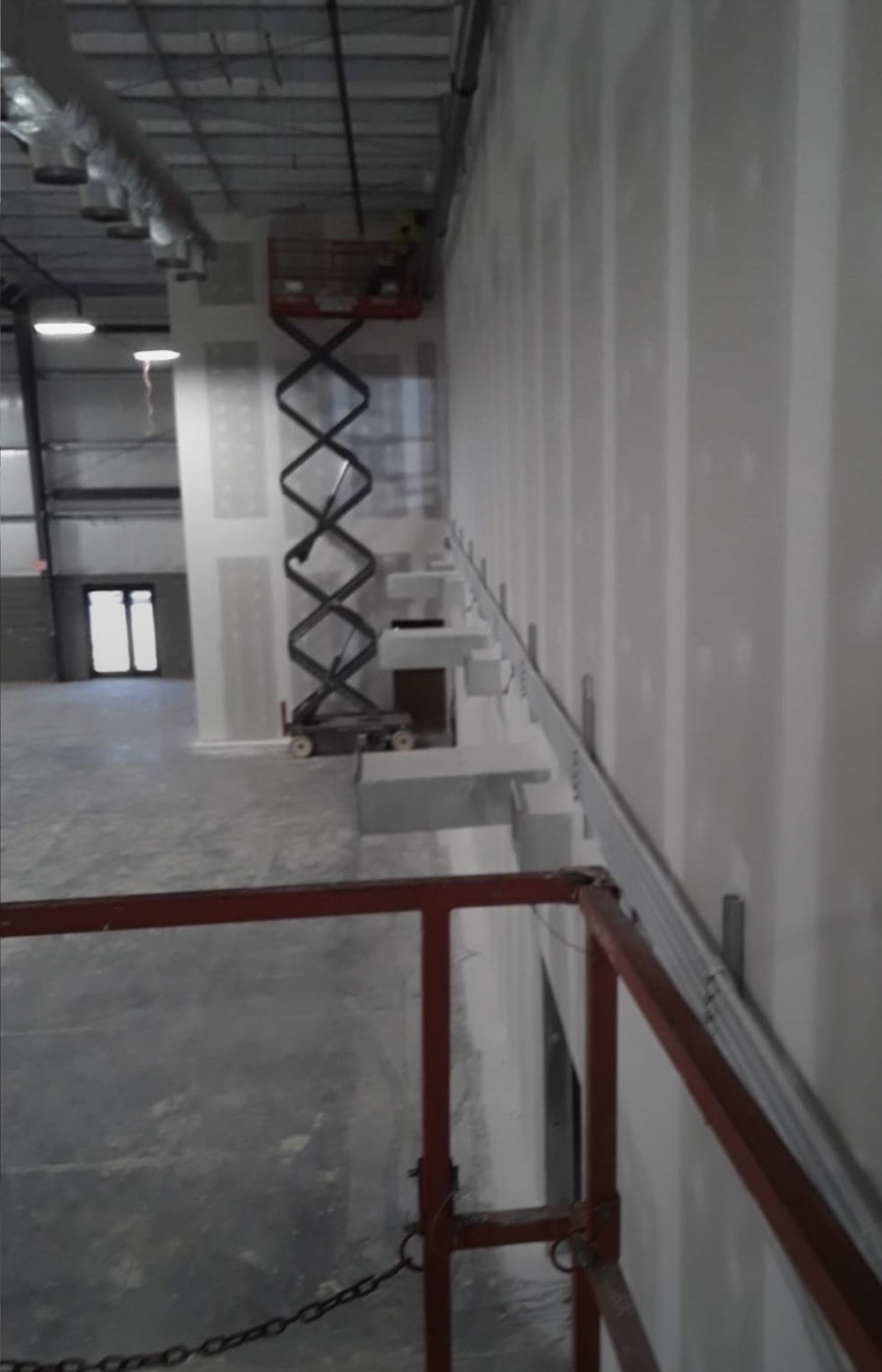Elevated view of a commercial interior with high-wall drywall hung and finished around structural columns